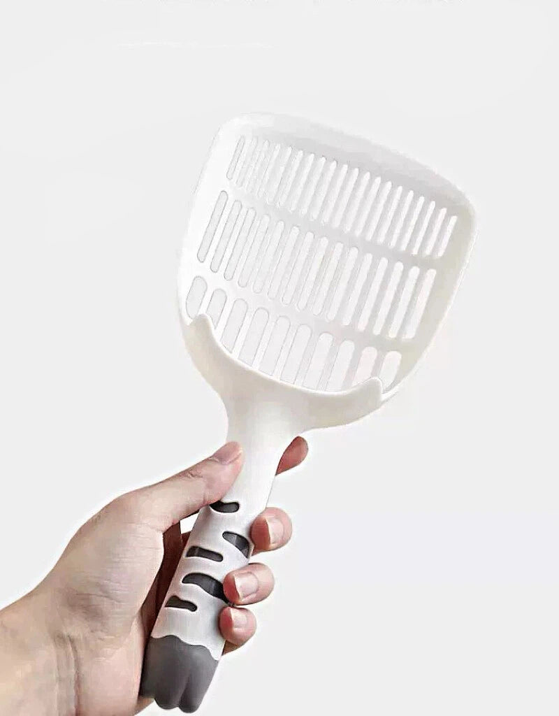 Hand holding a white plastic slotted scoop with black grip, suitable for pet litter cleaning