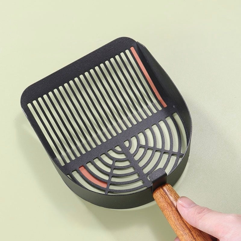 Black metal grill cleaning brush with wooden handle held by hand on light surface