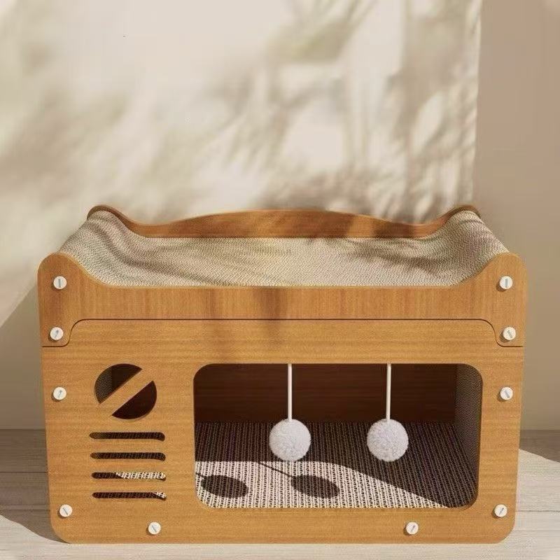 Wooden cat house with cushioned bed and hanging white pom-pom toys in soft natural light