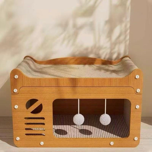 Wooden cat house with cushioned bed and hanging white pom-pom toys in soft natural light