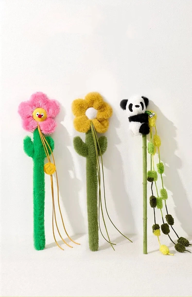 Three fuzzy flower-shaped pen toppers including pink and yellow flowers and a panda on green stems