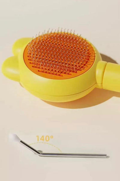 Yellow and orange pet grooming brush with stainless steel pins and angled metal ear cleaner