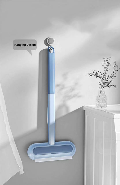 Blue hanging squeegee with ergonomic handle mounted on light gray wall near white cabinet and decorative vase